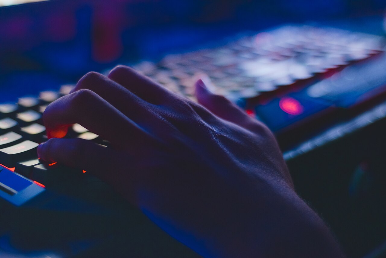 Hands typing on a backlit computer keyboard